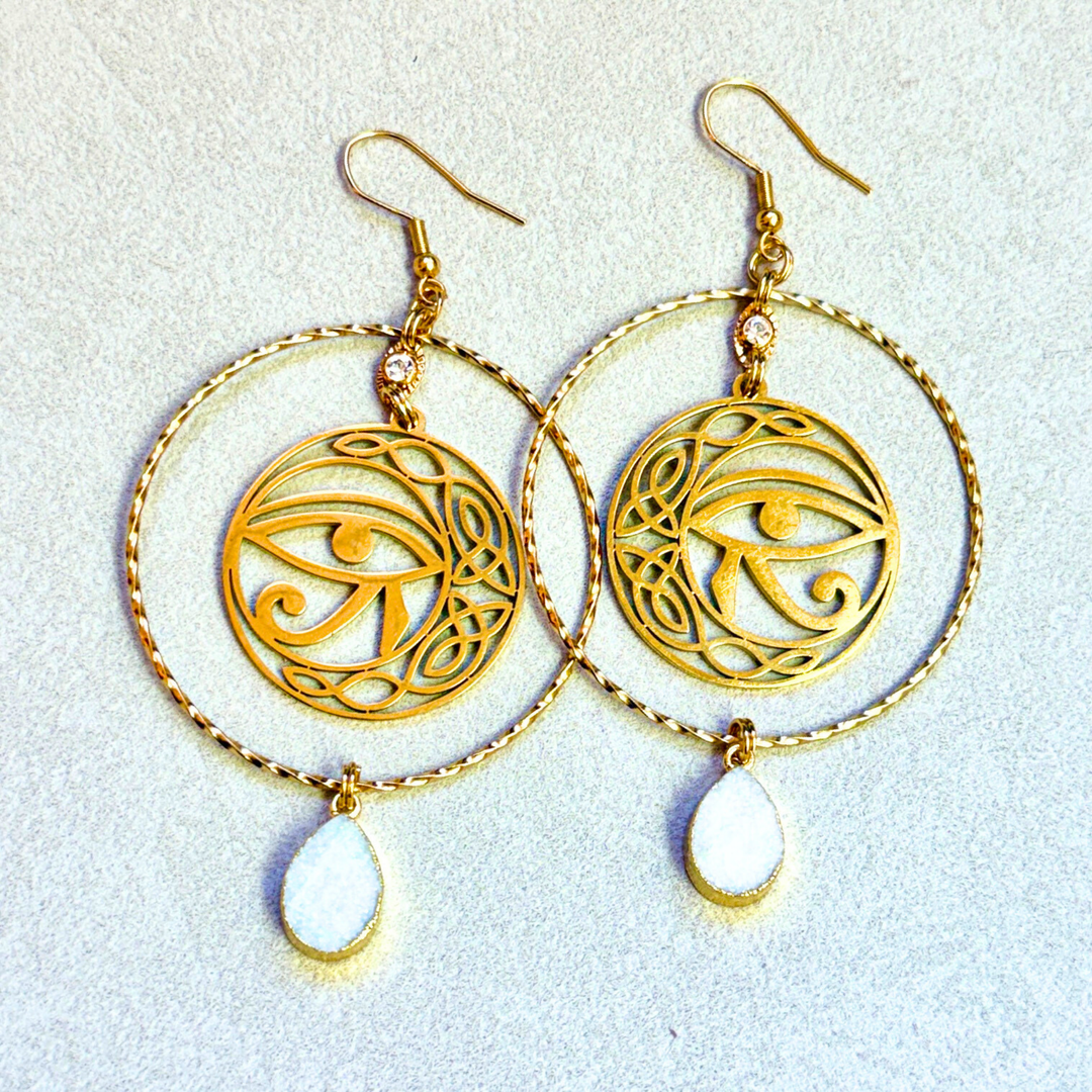 Statement gold hoop earrings with sparkling druzy stone and Eye of Horus charm. 18K gold plated stainless steel, hypoallergenic, tarnish resistant, and stunning.